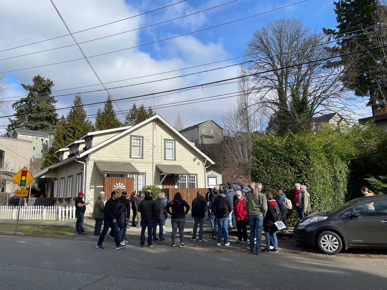A group of community members gather around an example of Middle Housing during the walking tour of Lower Maywood.